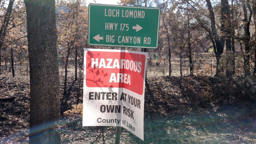 Road signage in front of a burned area.