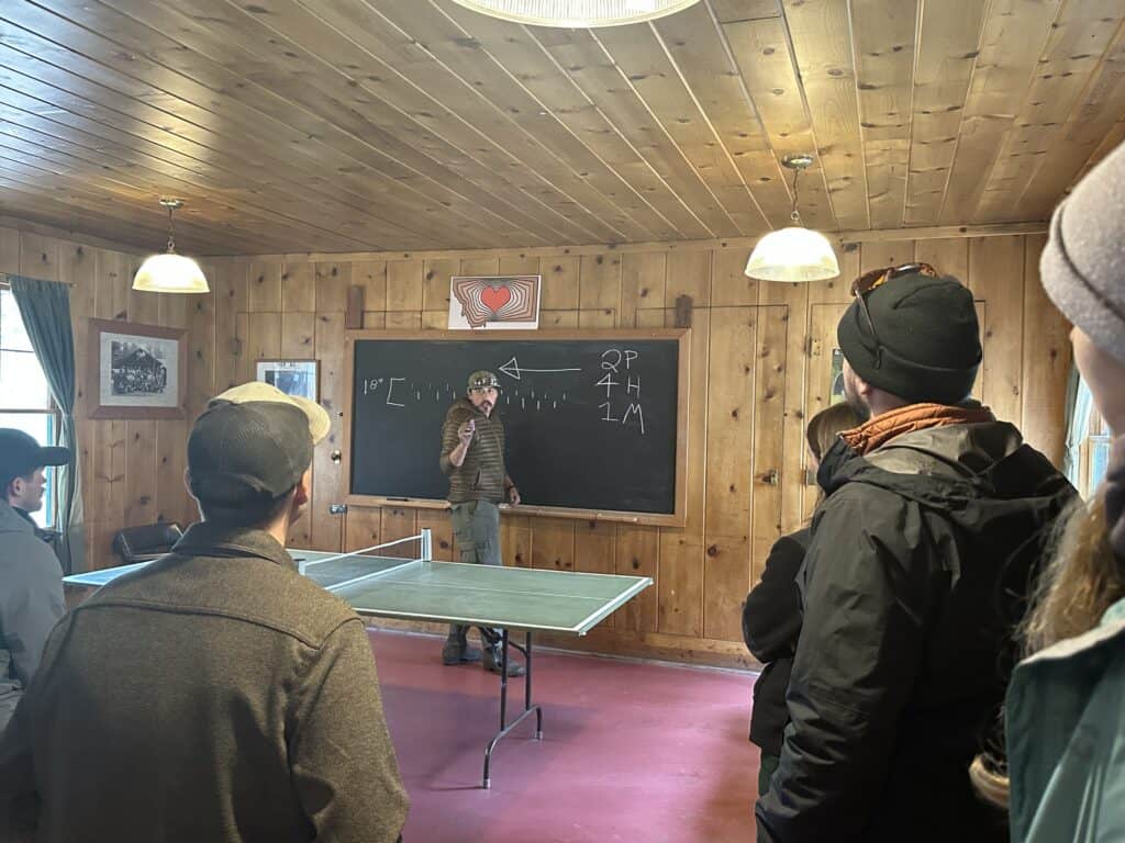 People gather in a wood paneled classroom.